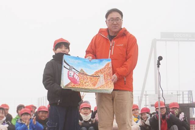 子どもたちが描いた絵をロープウエイの社長に手渡す様子