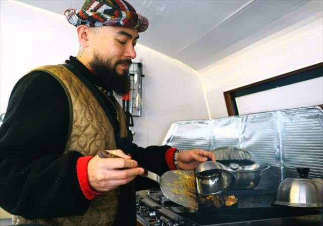 ジャマイカ料理店「J.J Jerk」の河原竜哉さんがトレーラーハウスのキッチンでジャークチキンを調理している様子