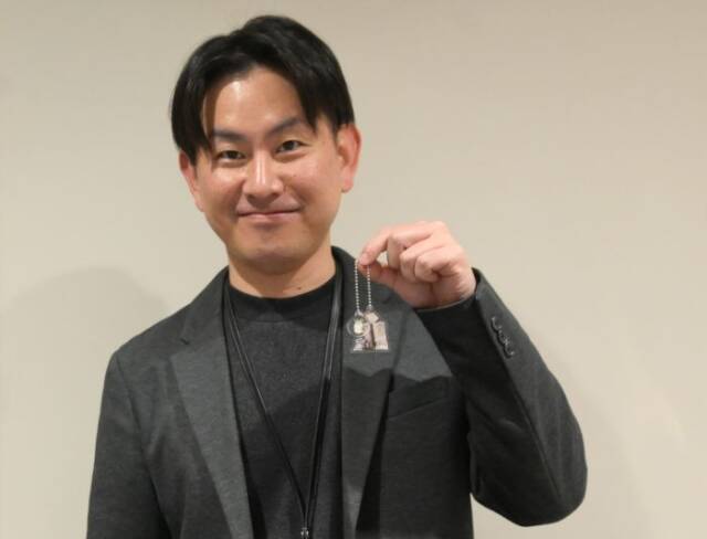 キーホルダーを手にする町企画情報課の藤井さん