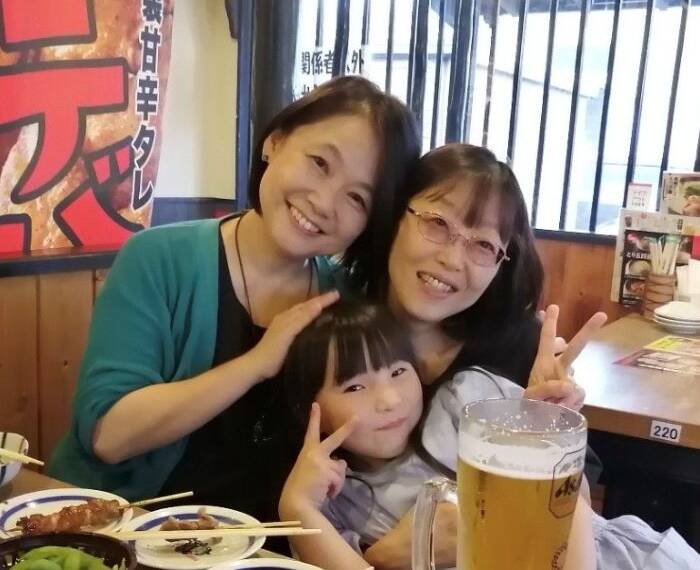 藤島さんと妹の森川さんと藤島さんの孫が焼き鳥屋で笑顔で写真を撮っている