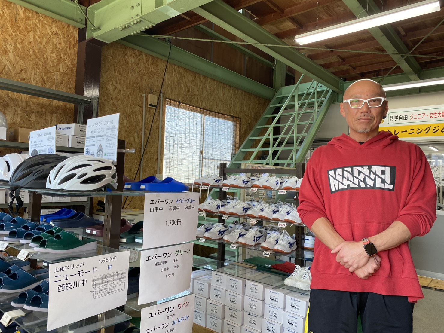 学校指定に上靴や体育館シューズを販売する店に立つ社長