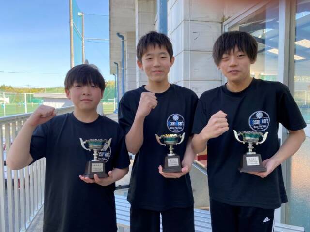 トロフィーを手にガッツポーズをする3人の選手