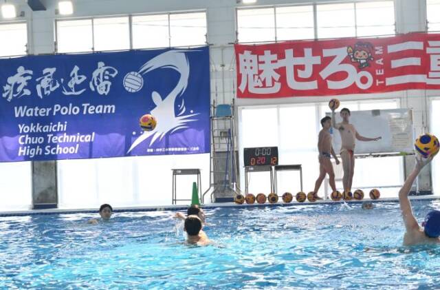 プールサイドから選手にボールを投げる様子