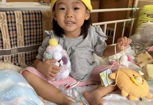 入院中のベッドの上でおもちゃを持つ笑舞ちゃん