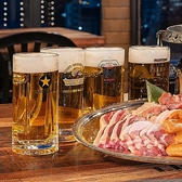 プラトンビアガーデンのテーブルに並ぶビールジョッキ。奥にBBQプレートが見える