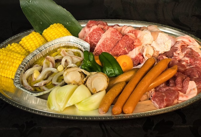 プラトンビアガーデンのミックスBBQプレート。牛肉・豚肉・ウインナー・野菜・とうもろこしが大皿に盛られている