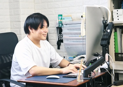 パソコンに向かい、笑顔で仕事をこなす則近社長