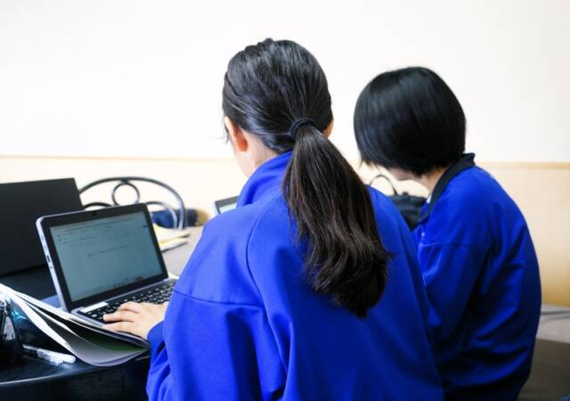 メモを見ながらタブレットで記事構成を考える中学生