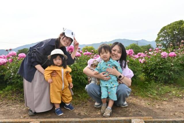 男の子と女の子の未就園児とその保護者の4人の写真背景にシャクヤク