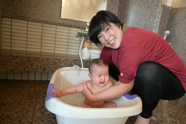 赤ちゃんをベビーバスで入浴させる助産師