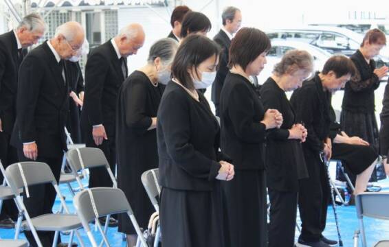 手を合わせて黙とうを捧げる参列の女性ら