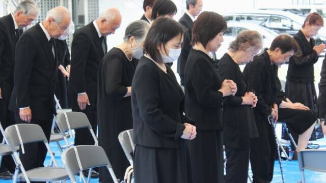 手を合わせて黙とうを捧げる参列の女性ら