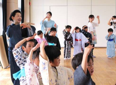 幼稚園で踊り方を教える西川千穂寿さん(左)。奥は妹の真希寿さん