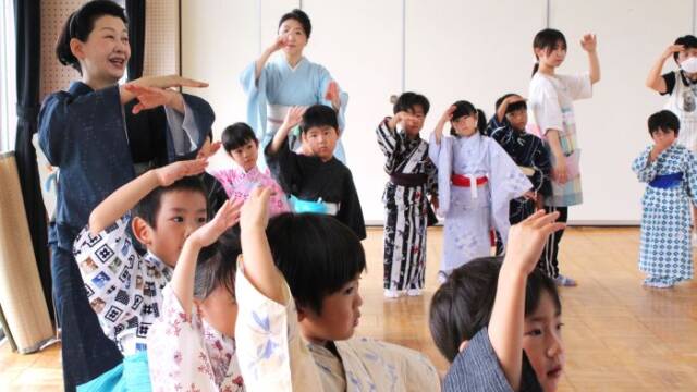 幼稚園で踊り方を教える西川千穂寿さん（左）。奥は妹の真希寿さん