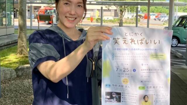 講演会「とにかく笑えればいい」のポスターを持つ人