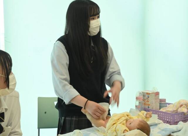保育の授業でおむつ替えをする生徒