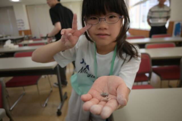 発掘した化石を手にしてVサインする子ども