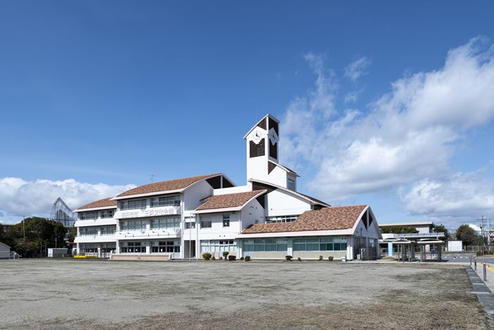 四日市市海山道町にある四日市市三浜文化会館(カルチュール三浜)の外観写真。青空の下、建物の全景と、その前に広いグラウンドがある様子