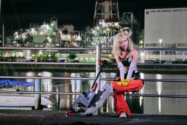 四日市ドームの裏側の道路でコンビナートを背景にポーズをとるコスプレイヤー