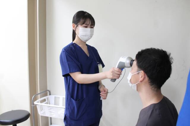 手持ち型の網膜電位図測定器(レチバル)を当てて検査を行っている様子。