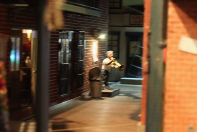路地の奥で楽器の練習をする少年の姿