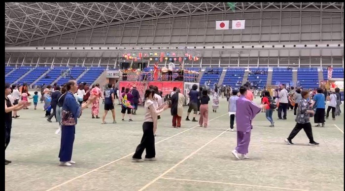 中央のやぐらを囲むように、来場者たちが輪になって盆踊りをしている