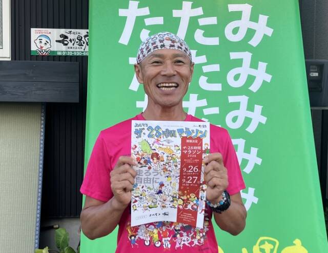 畳店の店主・石川さんが店前でチラシを手によんてつマラソンの参加を呼び掛けている