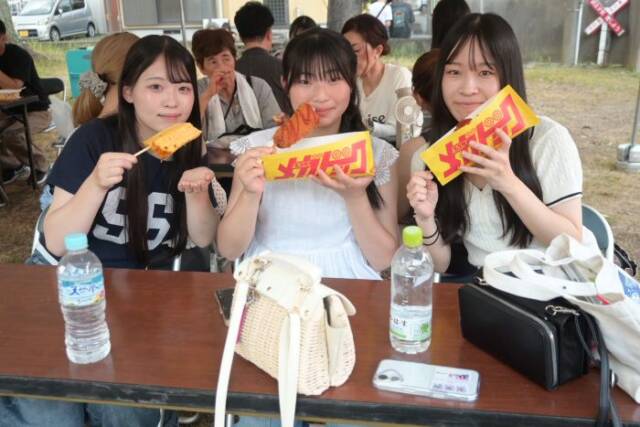 屋台の料理を手にして微笑む女子高校生3人