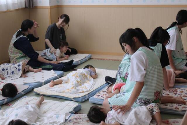 子どもたちのお昼寝に付き添う高校生ら