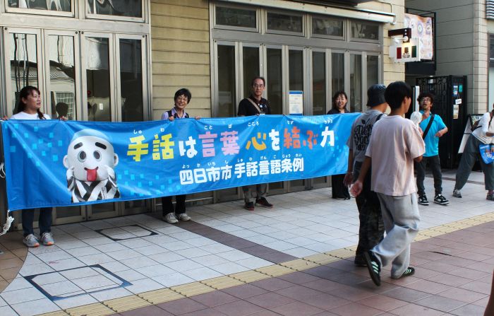 横断幕で手話への理解を求めながらのチラシ配り