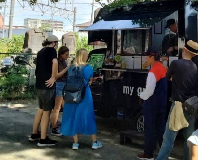 キッチンカーの前でメニューを選ぶ人