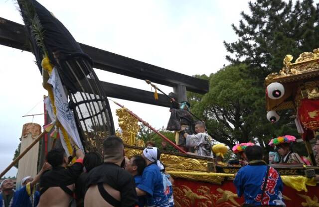 鳥居の前で鯨を仕留める演技をする子ども