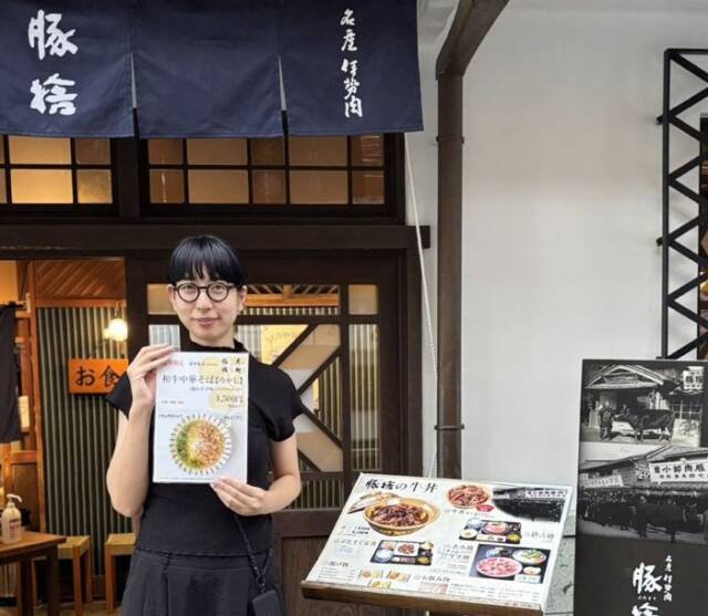 豚捨の店頭で和牛中華そばのメニューを持つ南野さん