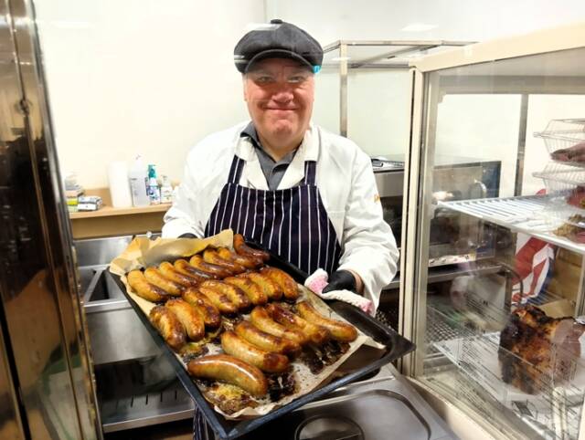 「リッシュマンズ」のスタッフが焼きたてソーセージの載った鉄板を見せている