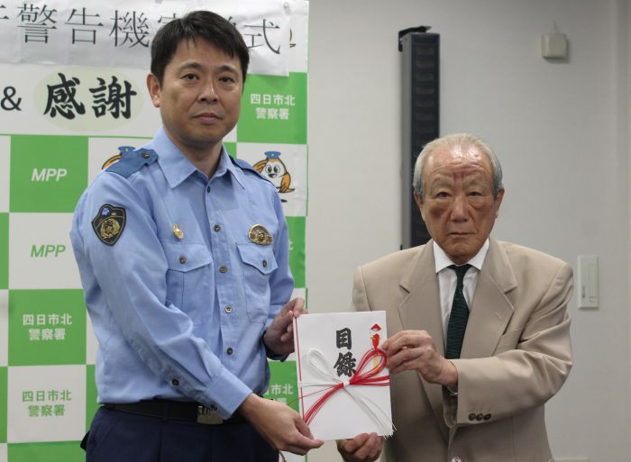 寄贈の目録を尾嵜隆則四日市北署長に手渡した生川平藏さん
