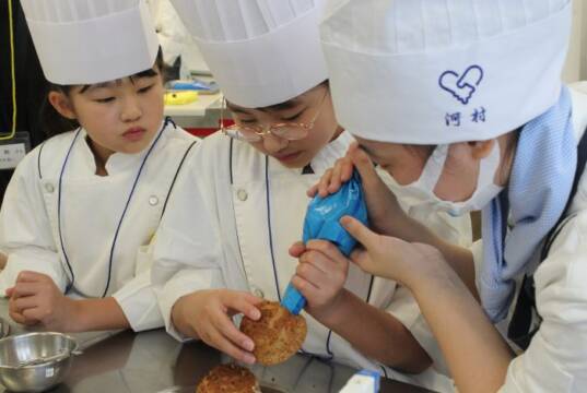シュークリームのクリーム詰めを体験する子どもたち