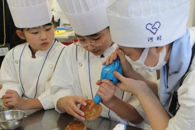 シュークリームのクリーム詰めを体験する子どもたち