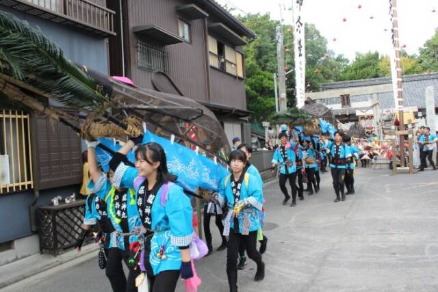 竹組みのクジラを運ぶ女の子ら