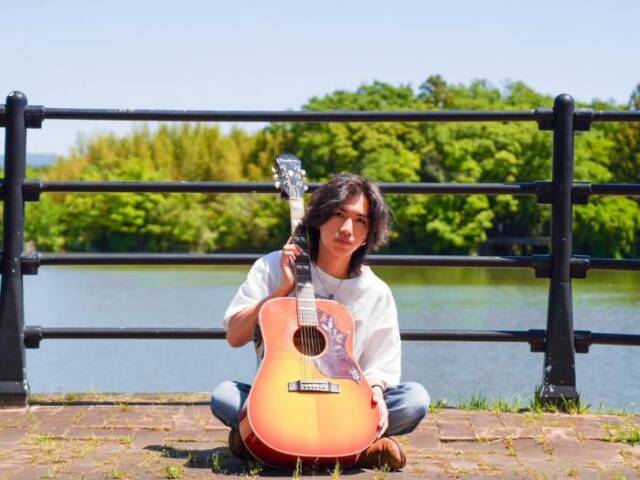 ギターを持って座る中川さん