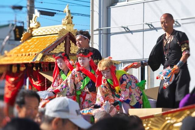 演技を終えた大正丸の船上から、3人の踊り子が集まった人たちに菓子を渡している
