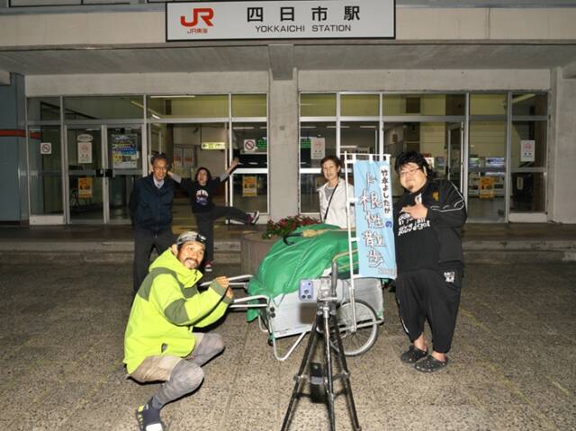 JR四日市駅で、スマートフォンを三脚にセットし、出迎えた人々と記念撮影する竹永よしたかさん