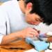 展足板の上で昆虫の羽や脚の位置をピンセットで整え、真剣な表情で標本を制作する椎名奏衣さん